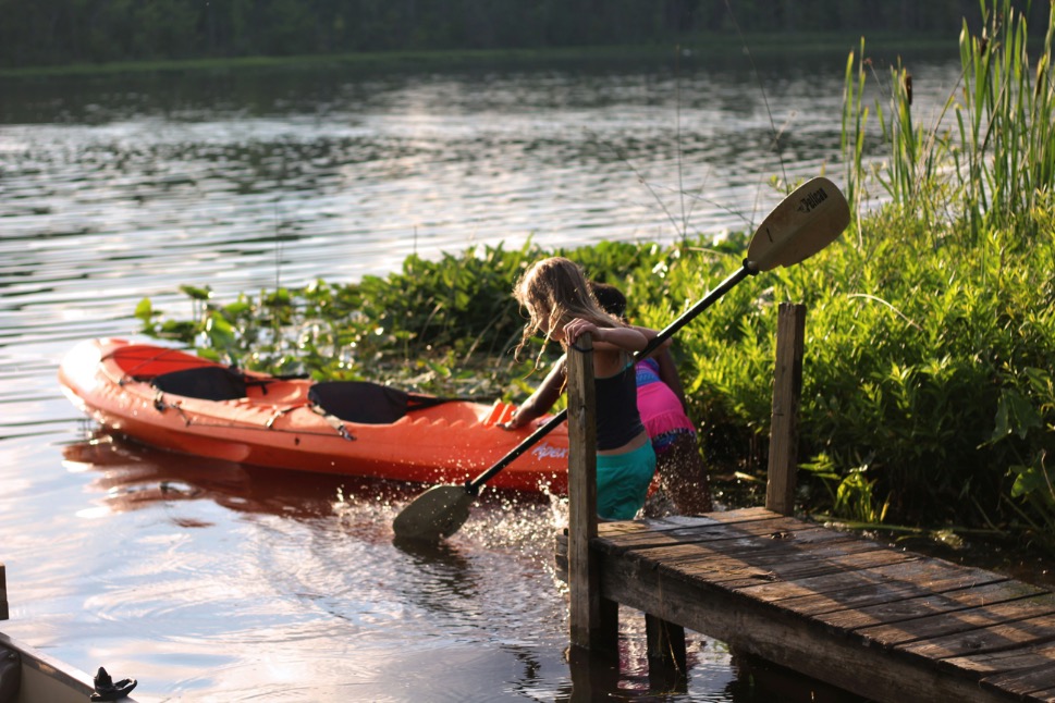 A skilled kayak instructor leading children in an outdoor adventure, teaching water safety and fostering a love for nature