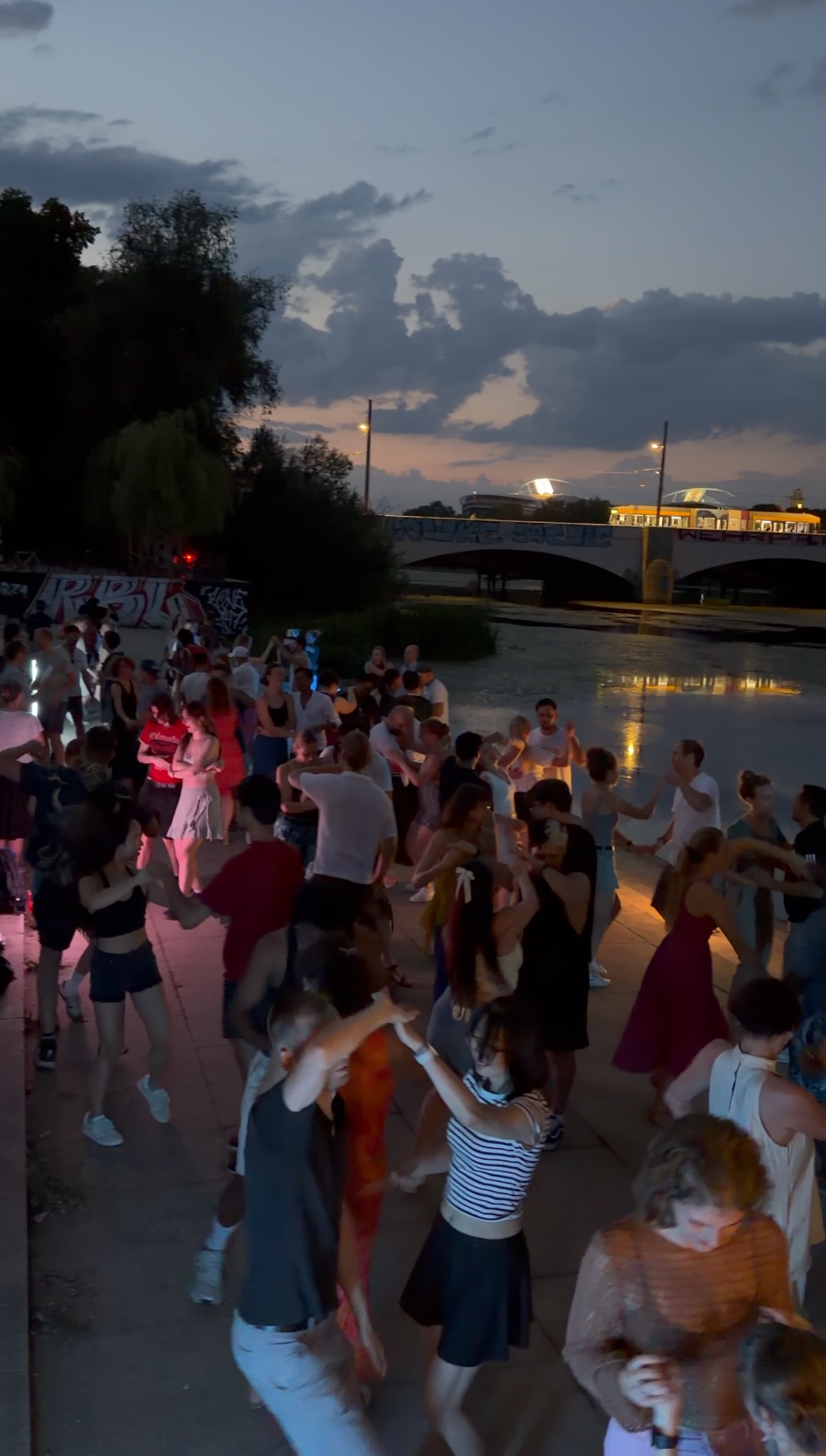 Viele Menschen tanzen bei einem Salsa-Social am Fluss in der Abenddämmerung