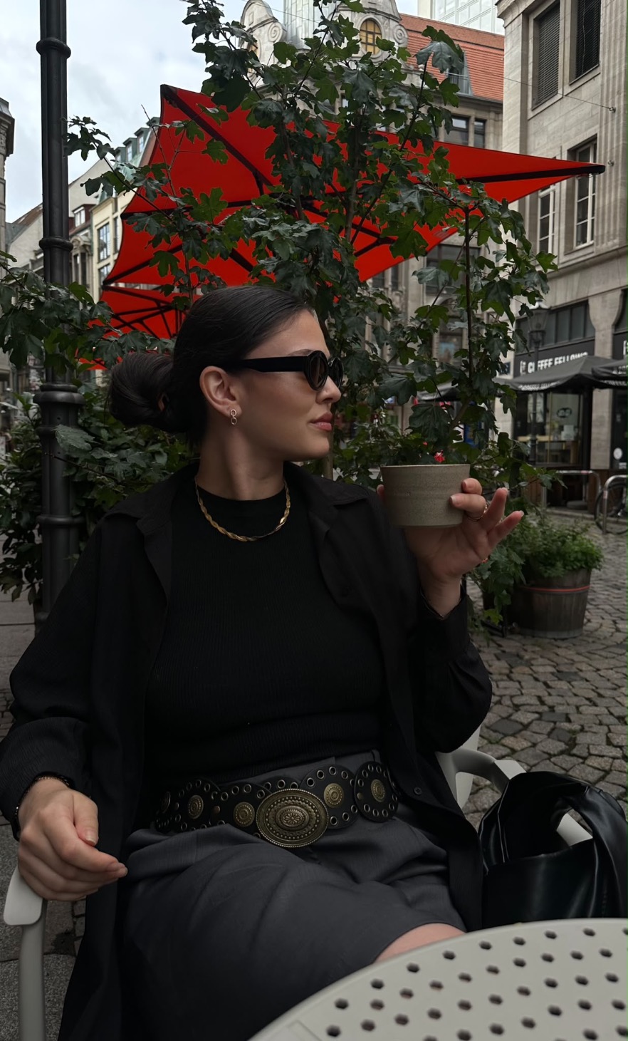 Franzi mit einem Kaffeebecher an einem Tisch im Freien