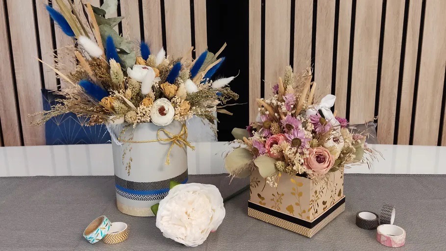 Zwei dekorative Boxen mit Blumenarrangements in Blau, Weiß und Rosa
