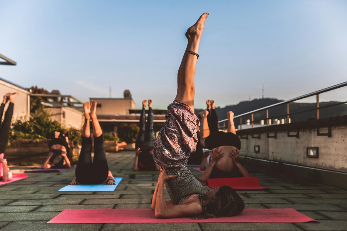 People practicing yoga poses during sunset on a urban rooftop with city skyline in the background