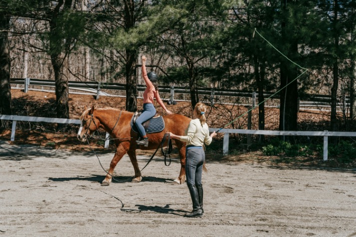 Beginner riders learning horsemanship skills under professional guidance in an outdoor arena